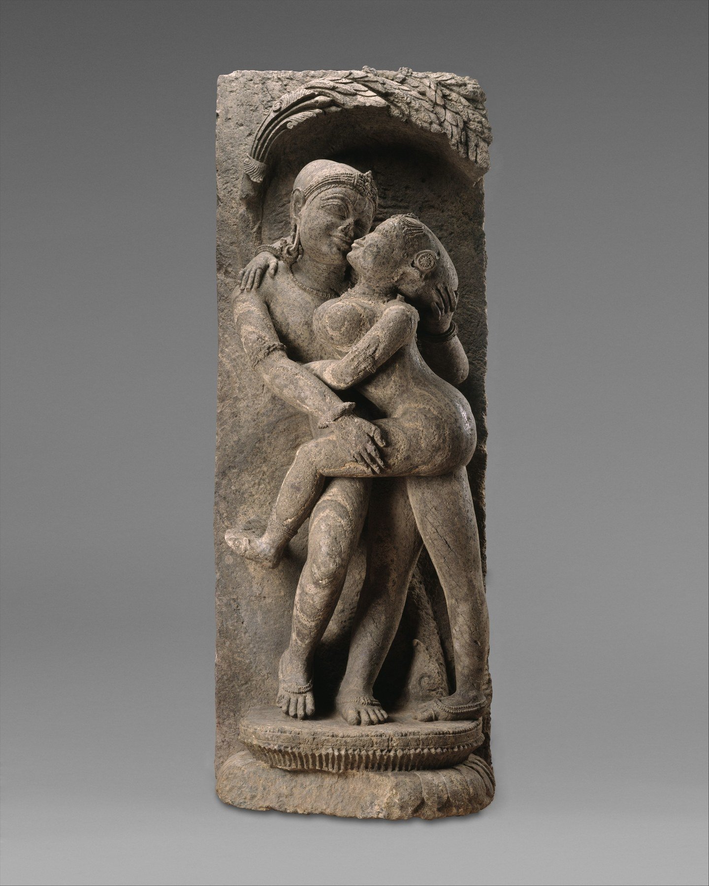 Sandstone temple sculpture of an embracing adult couple.
