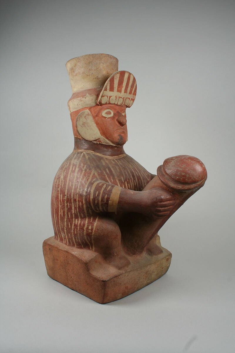 Moche ceramic stirrup-spout vessel depicting a seated adult male figure holding an exaggerated phallus.
